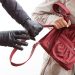 A closeup of a thief wearing gloves holding a woman's bag