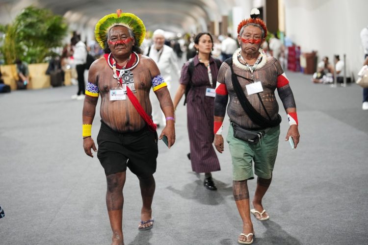 Akjabor Kaiapo, a Brazilian Indigenous activist, left, walks through the venue for the COP30 U.N. Climate Summit, Tuesday, Nov. 11, 2025, in Belem, Brazil. (AP Photo/Andre Penner)