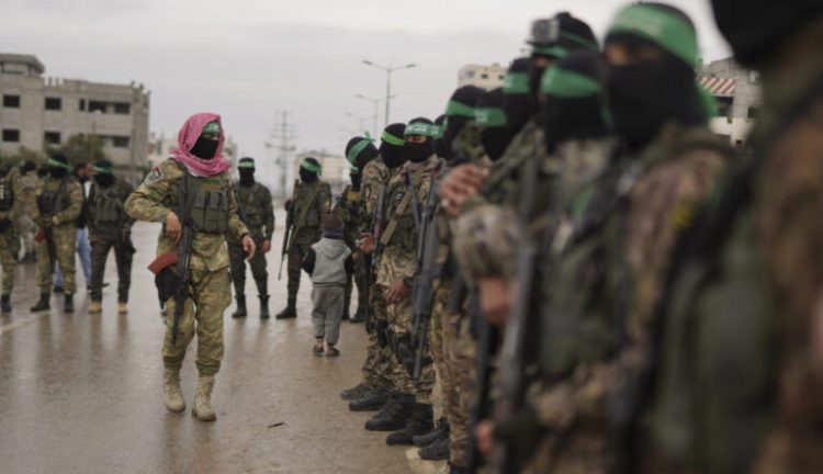 CORRECTS THE NAME OF THE CITY AS NUSEIRAT - Hamas fighters stand in formation ahead of the planned release of Israeli hostages set to be handed over to the Red Cross in Nuseirat, Gaza Strip, Saturday, Feb. 22, 2025. (AP Photo/Abdel Kareem Hana)
