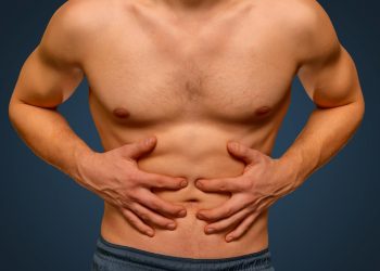 Unrecognizable man compresses the abdomen due to pain