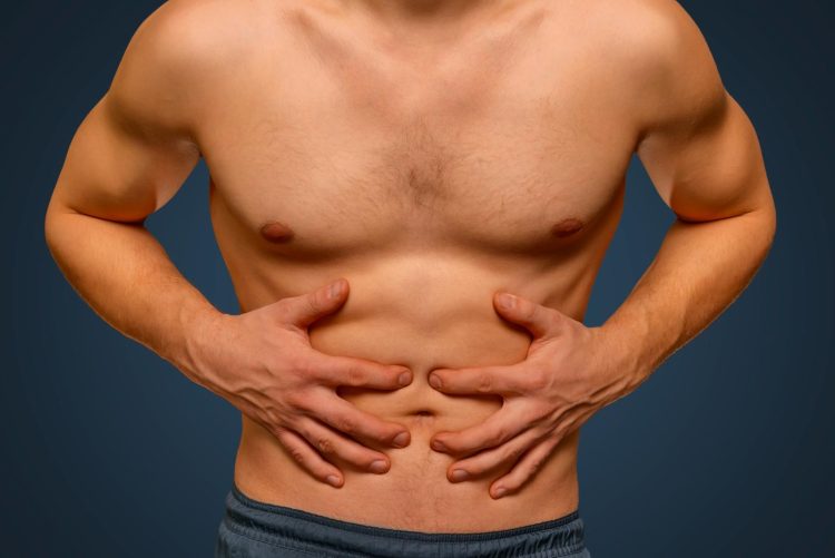 Unrecognizable man compresses the abdomen due to pain