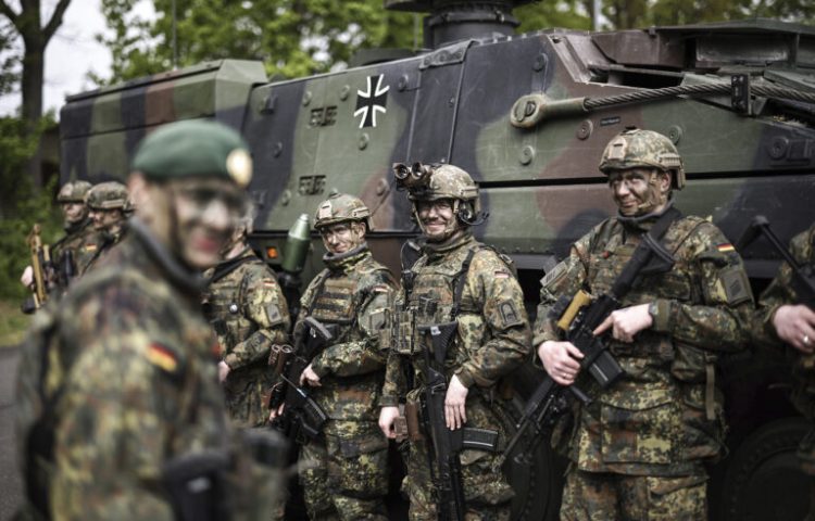Soldiers of the German forces, Bundeswehr, stand in front of a Boxer military vehicle, a new type of armoured personnel carrier, at the Julius Leber Barracks in Berlin, Germany, Wednesday, April 24, 2024. (Henry Nicholls/Pool Photo via AP)