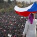 A woman waves a Czech flag from a roof as people take part in a large anti-government protest in Prague, Czech Republic, Saturday, Nov. 16, 2019. Czechs are rallying in big numbers to use the 30th anniversary of the pro-democratic Velvet Revolution and urge Prime Minister Andrej Babis to resign as peaceful protesters from all corners of the Czech Republic are attending the second massive protest opposing Babis at Letna park, a site of massive gatherings that significantly contributed to the fall of communism in 1989. (AP Photo/Petr David Josek)