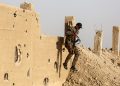 A member of the Kurdish People's Protection Units (YPG) jumps from a wall as he carries a Kalashnikov assault rifle in the town of al-Karamah, 26 kms from the Islamic State (IS) group bastion of Raqa, on May 10, 2017. / AFP PHOTO / DELIL SOULEIMAN